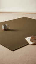 Olive brown wool blend rug, allowing viewers to perceive both surface detail and overall shape within an inviting setting...